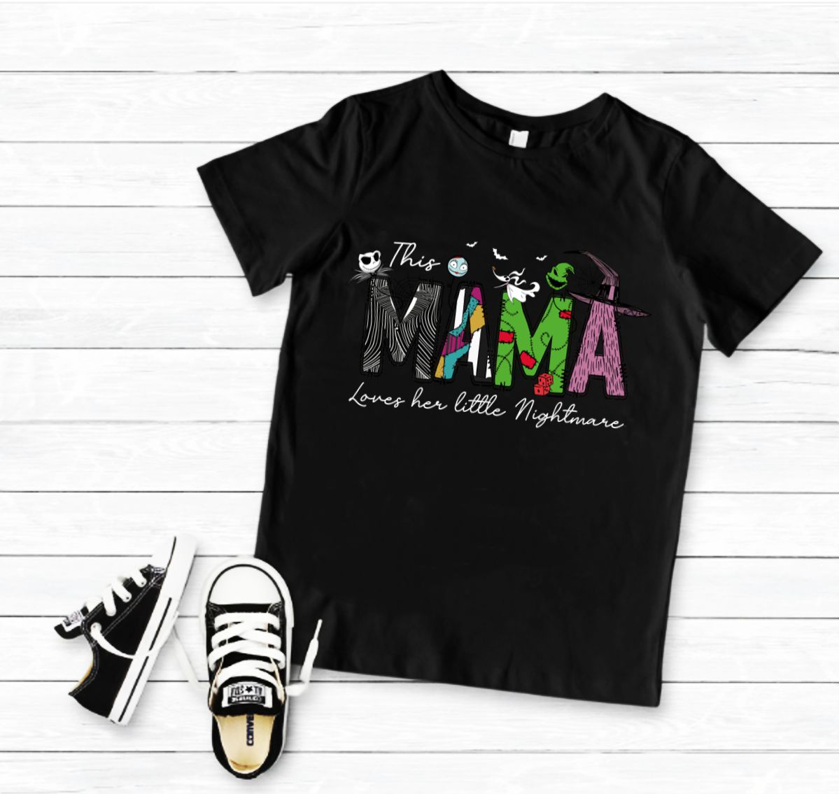 Camiseta preta com estampa colorida e ténis pretos e brancos ao lado sobre fundo branco.