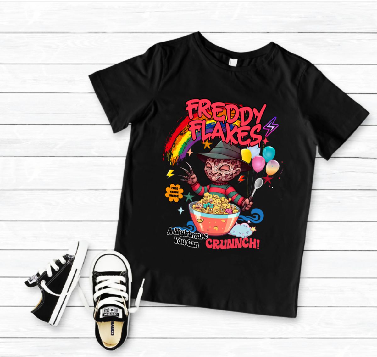 T-shirt preta com estampa colorida 'FREDDY FLAKES' e ténis pretos ao lado