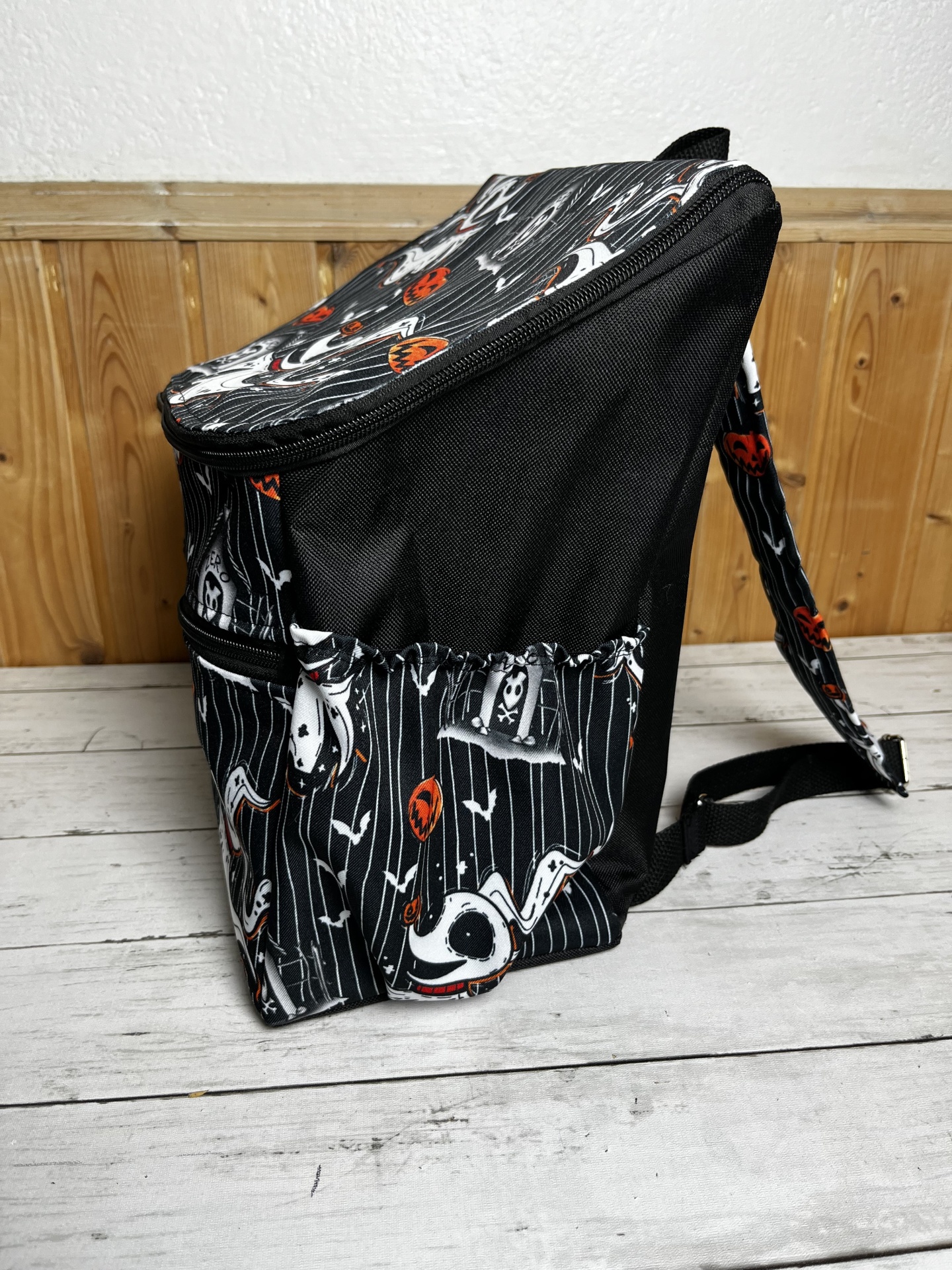 Mochila preta com padrão de Halloween com fantasmas e abóboras.