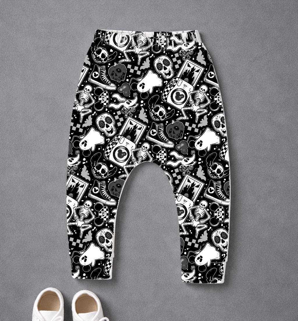 Calças com padrão preto e branco de caveiras, esqueletos e símbolos variados, com sapatilhas brancas no chão