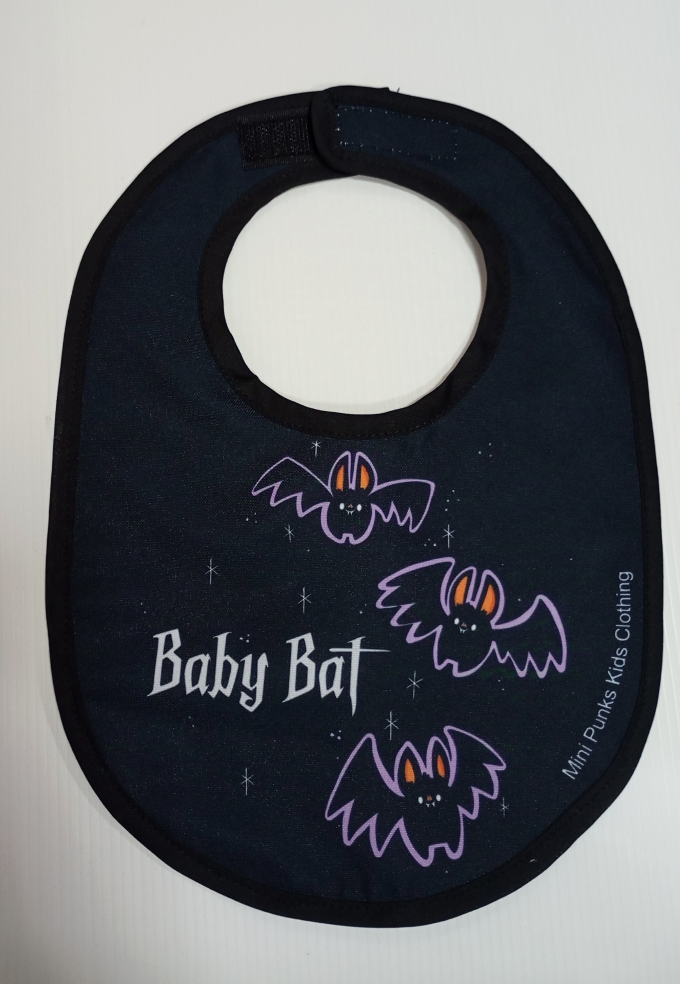 Babete preto com morcegos roxos e texto Baby Bat