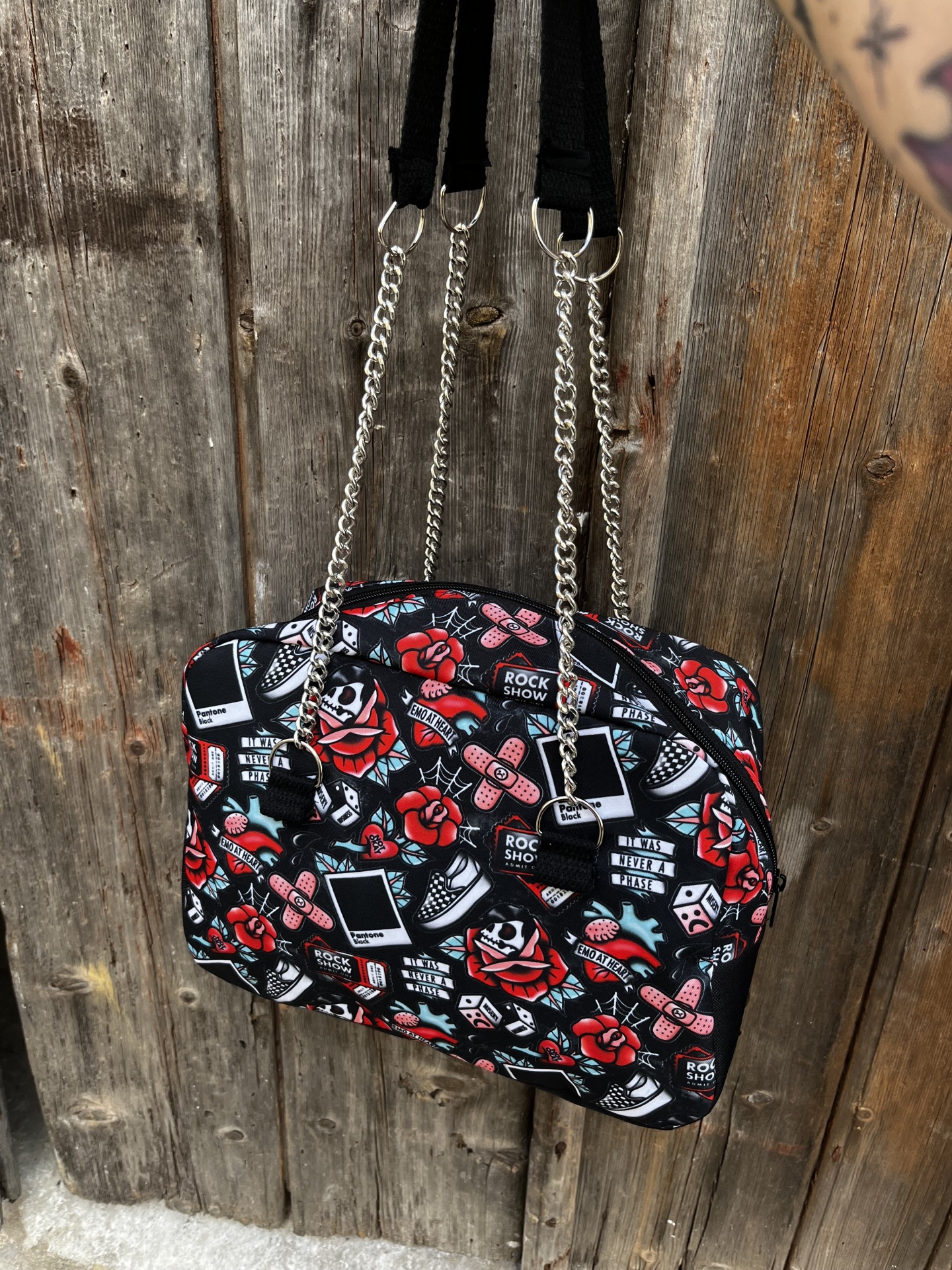 Mala tipo bolsa com padrão colorido com rosas, dados, sapatilhas e textos diversas pendurada em madeira