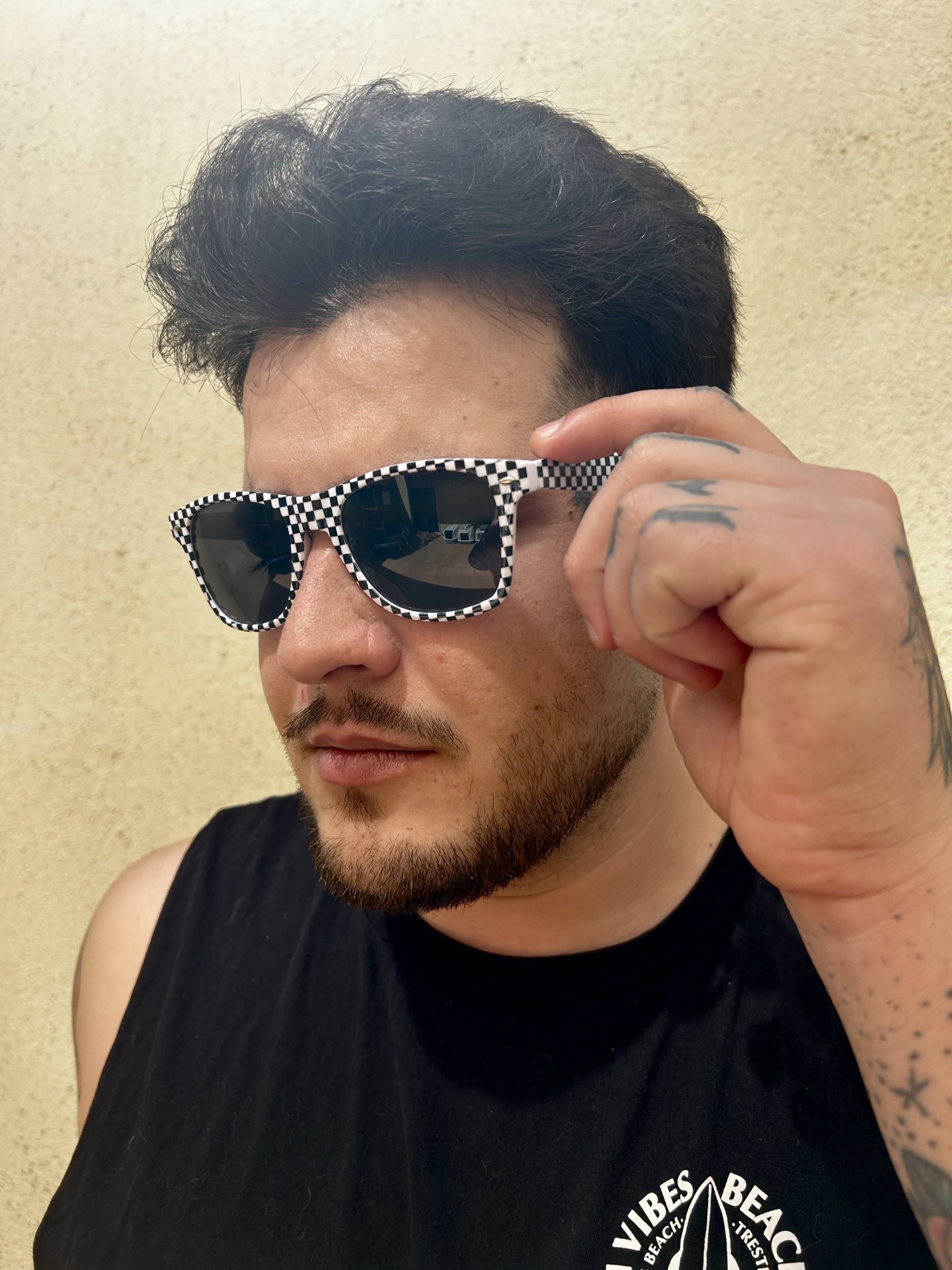 Óculos de sol com armação xadrez preto e branco usados por homem com camiseta preta