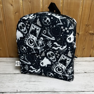 Mochila preta com estampado branco de caveiras, esqueletos e ícones diversos.