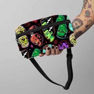 pochete preta com padrão colorido de monstros clássicos segurada por uma mão com tatuagens