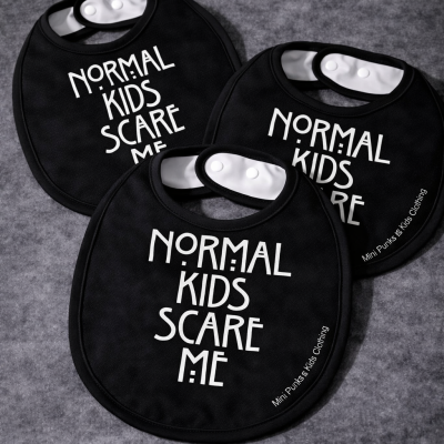 Três babetes pretos para bebés com texto branco e fecho de pressão.