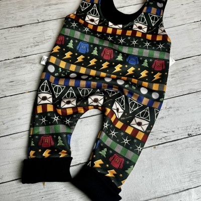 Macacão de bebé com padrão de símbolos de Harry Potter em tecido colorido.