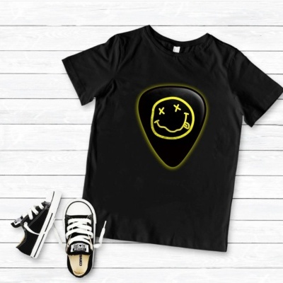 T-shirt preta com estampa de palheta e rosto sorridente, com ténis pretos ao lado, sobre chão de madeira branca