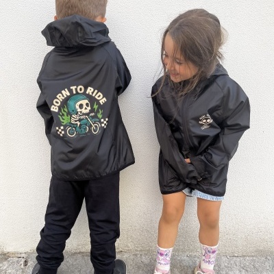 Crianças com casacos pretos com imagens e texto estampado