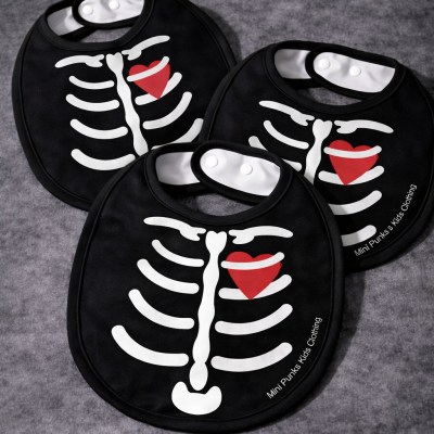 Babetes pretos para criança com estampa de esqueleto e coração vermelho.