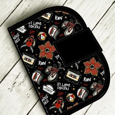 Carteira preta com estampas coloridas e textos em fundo de madeira clara