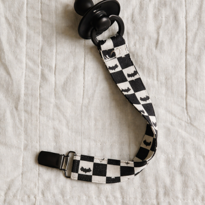 Chupeta preta com fita preta e branca aos quadrados com morcegos e prende de metal