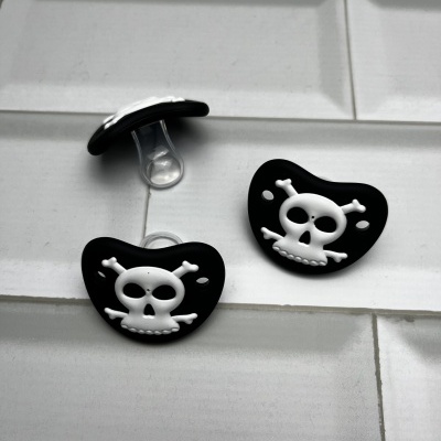Três chuchas de bebé pretas com caveira branca