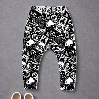 Calças com padrão preto e branco de caveiras, esqueletos e símbolos variados, com sapatilhas brancas no chão
