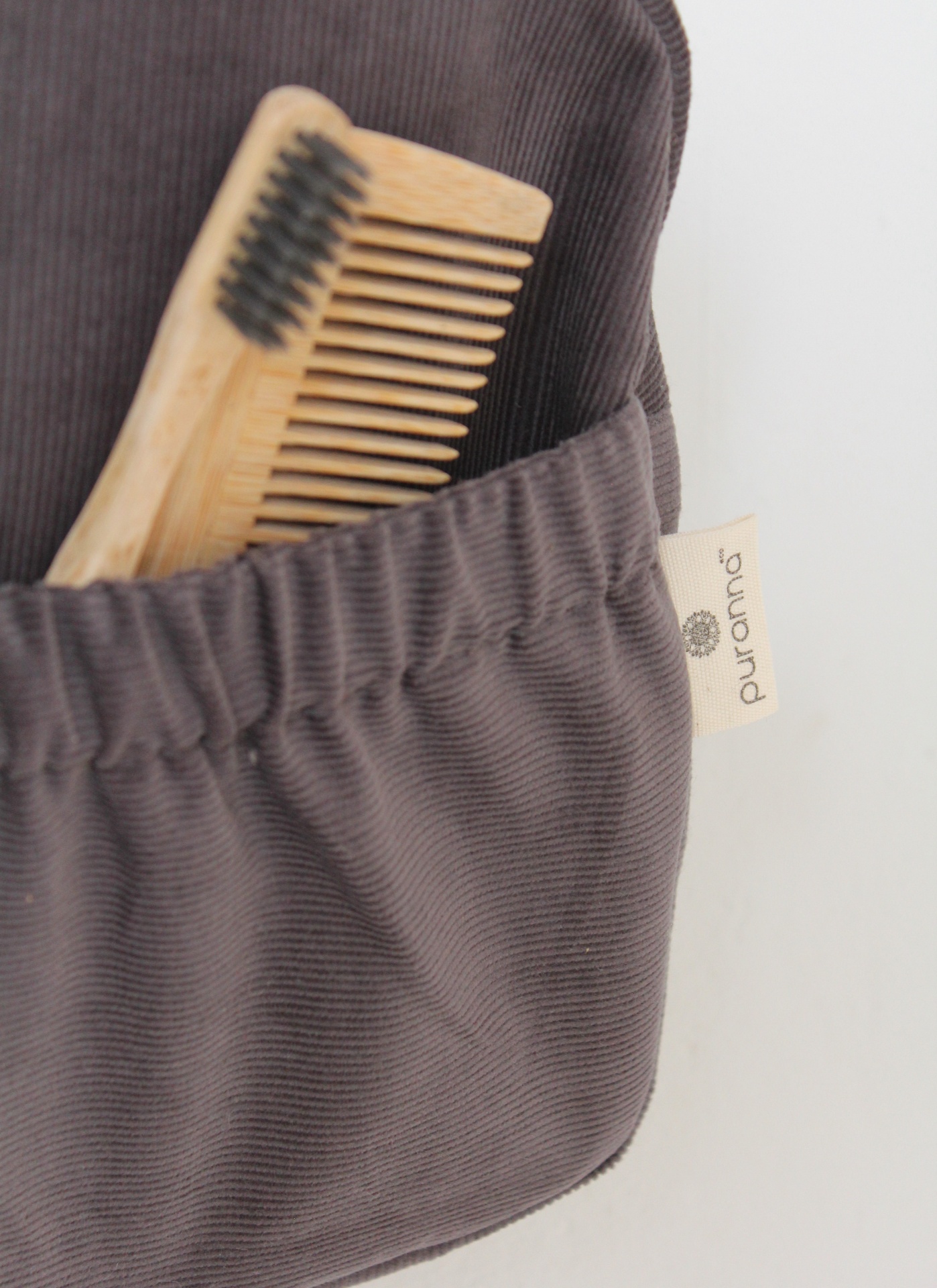 Pente de madeira com escova num bolso de tecido cinzento escuro