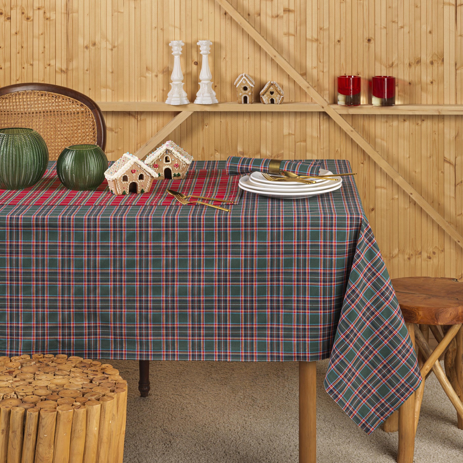Toalha de mesa xadrez em verde, vermelho e branco sobre mesa de madeira com decoração e parede de madeira ao fundo