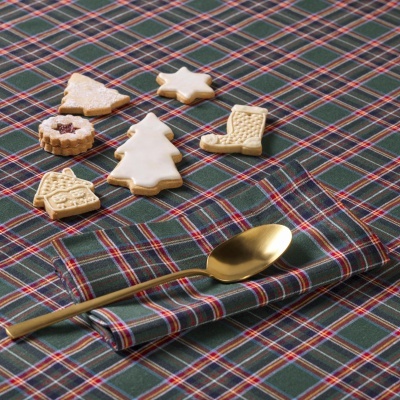 Mesa com toalha xadrez verde com bolachas decoradas de Natal e colher dourada