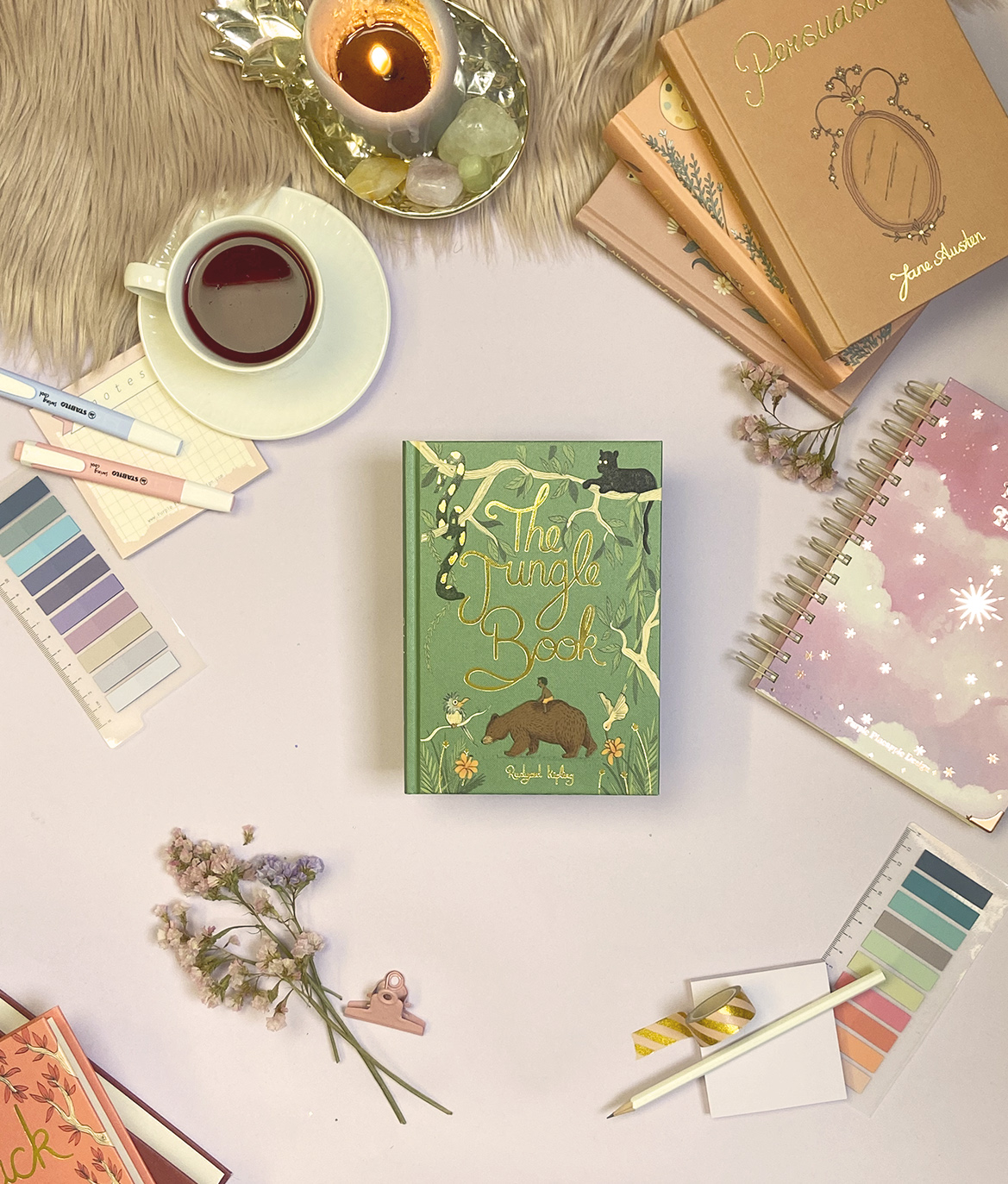 Mesa organizada com livro 'The Jungle Book', chá, velas e materiais de escrita