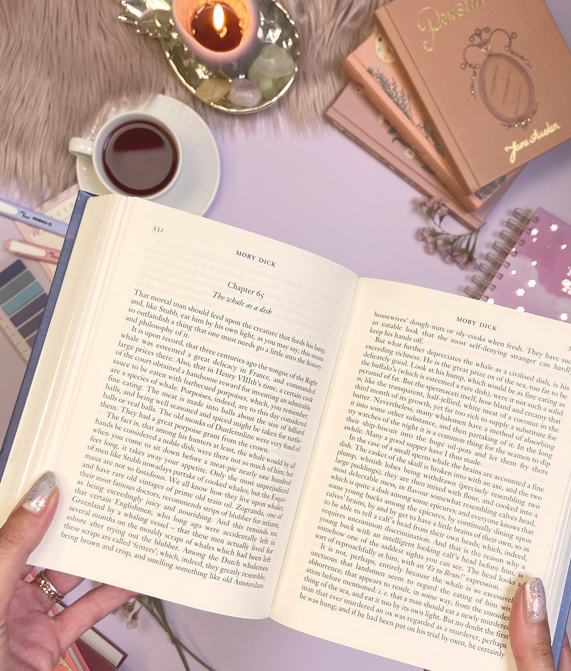 Livro aberto de Moby Dick com xícara de bebida, vela acesa e livros na mesa