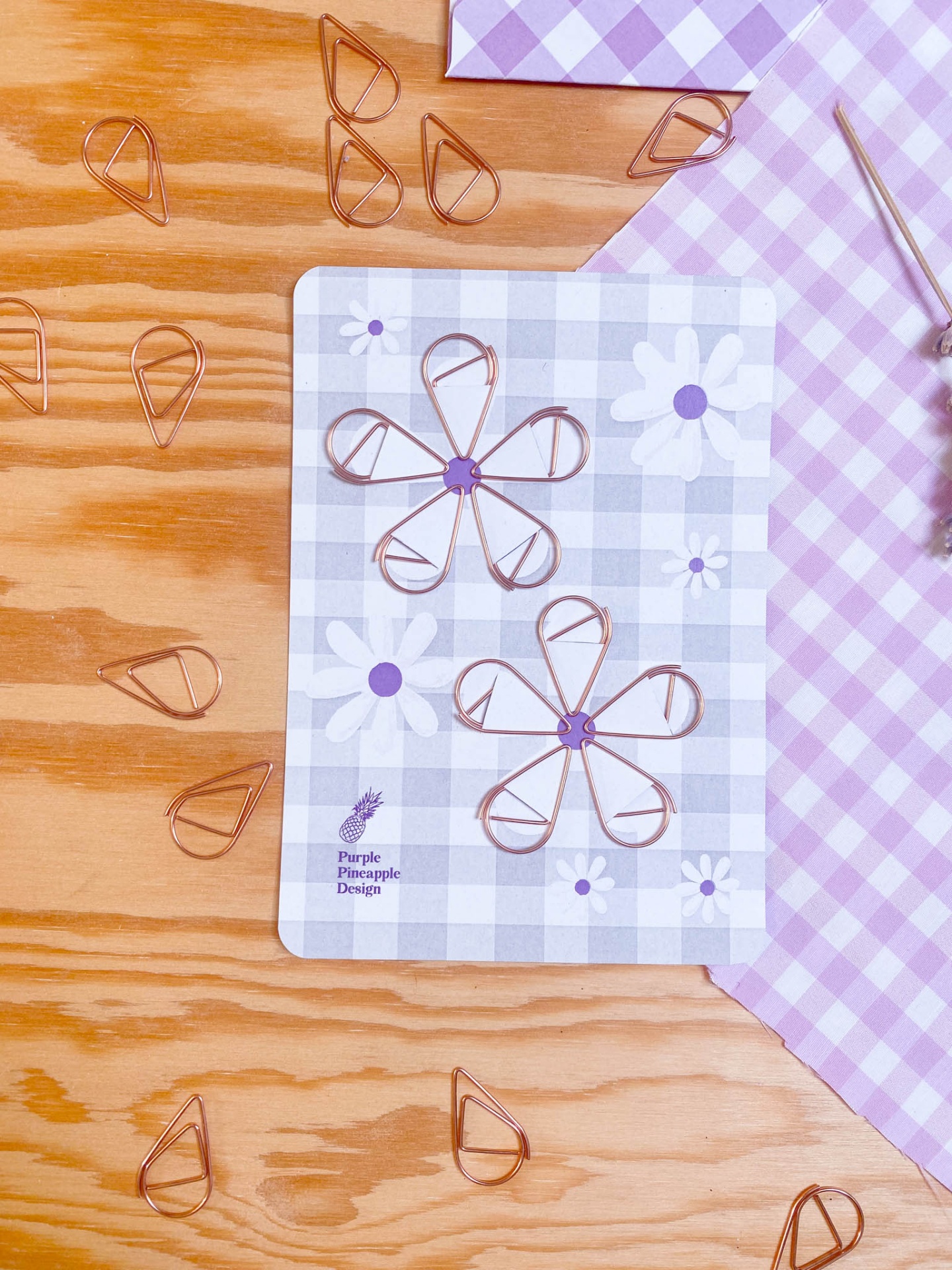 Clips de papel cobre em forma de pingo sobre caderno com padrão quadriculado e flores
