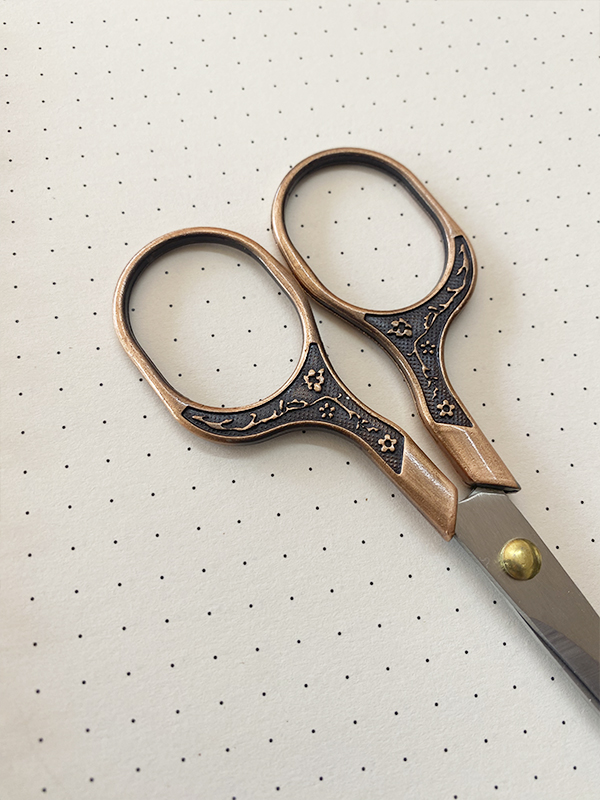 Tesoura de metal com punhos decorados em bronze com padrão floral e lâminas cinzentas