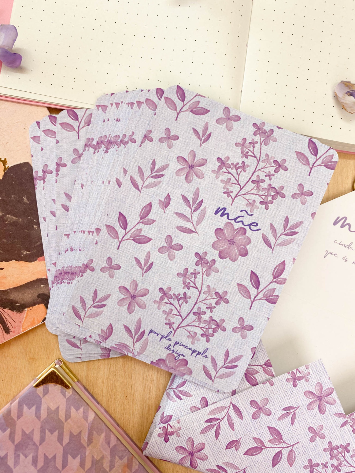 Cartas florais lilás com a palavra mãe, caderno e estojo sobre mesa de madeira