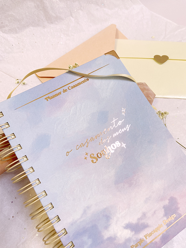 Caderno azul com letras douradas e envelopes em fundo branco