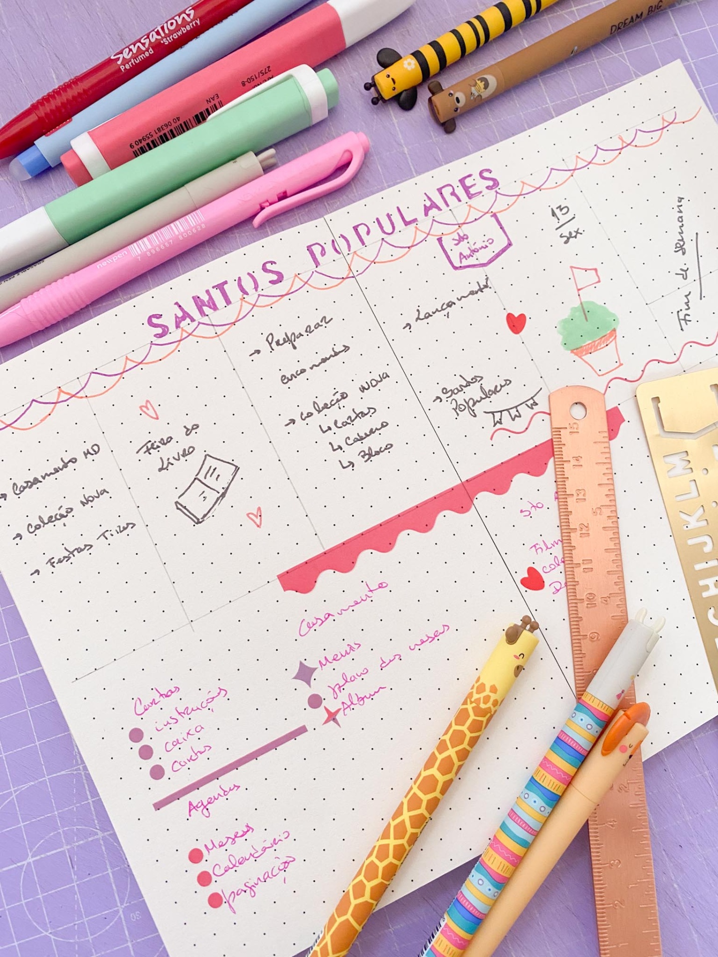 Folha com planejamento manuscrito com canetas coloridas, lápis e régua numa mesa lilás.