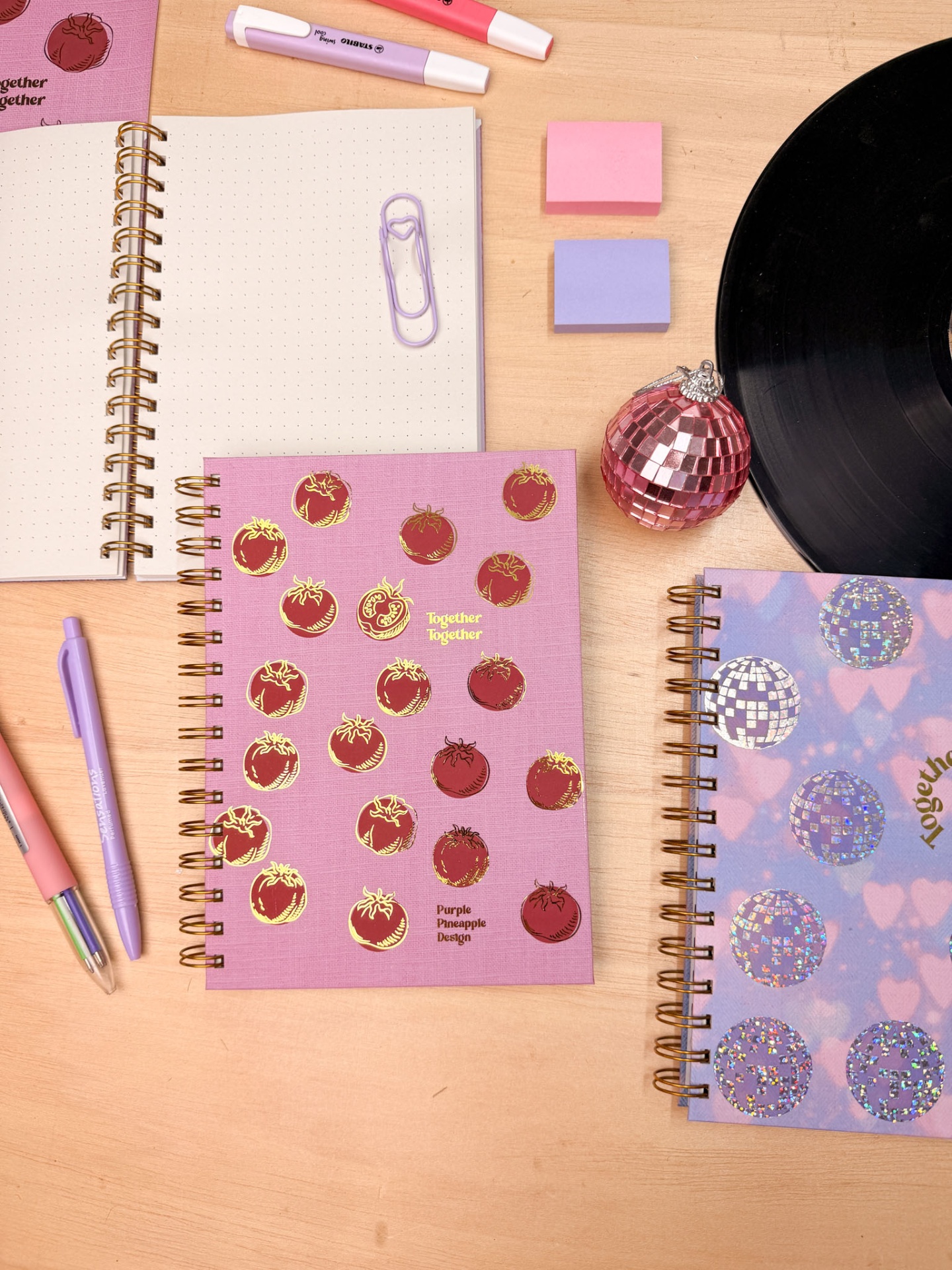 Cadernos espiral decorados com canetas, clips e acessórios em fundo de madeira