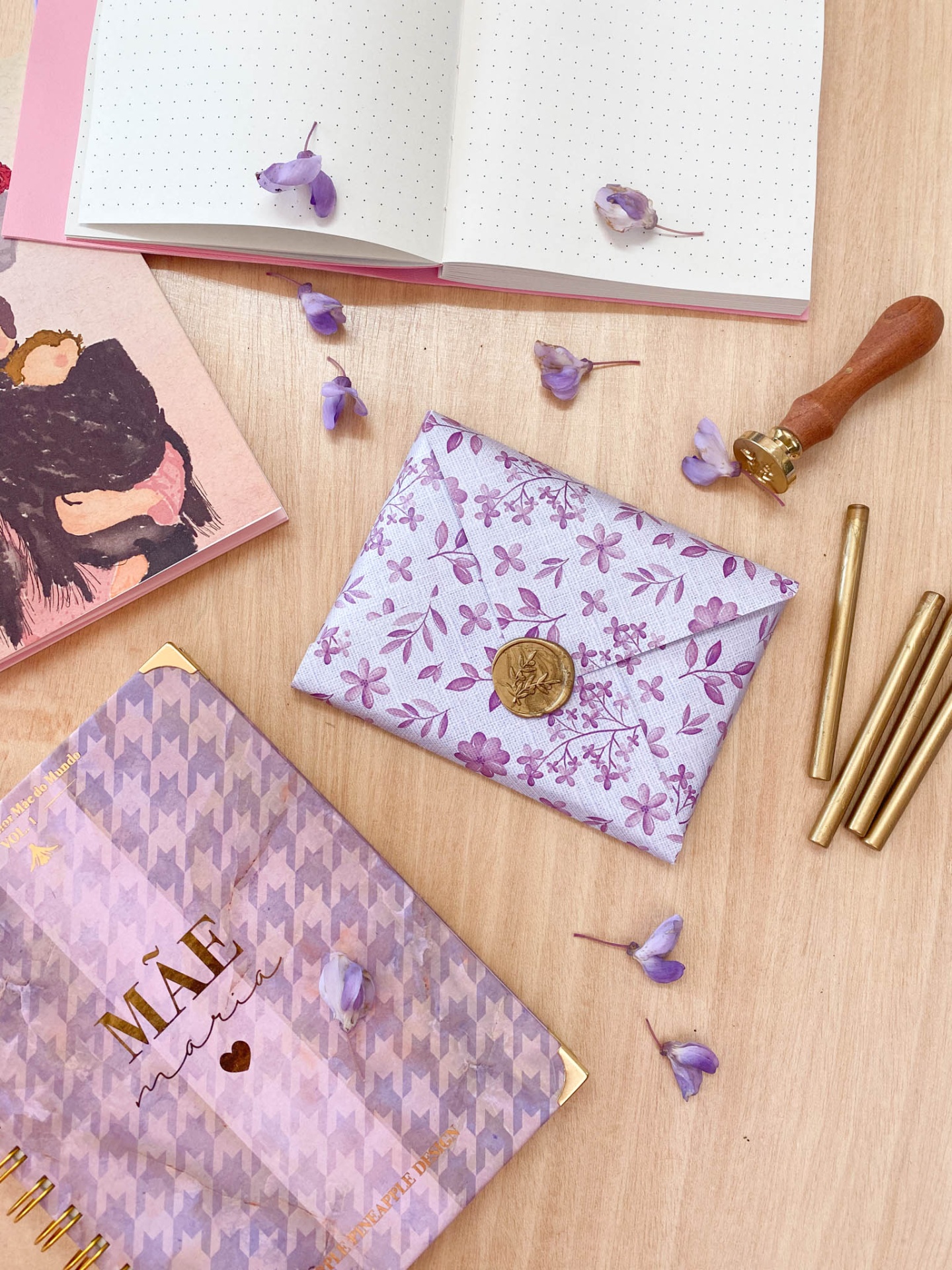 Carteira floral lilás em mesa com cadernos e flores lilás espalhadas