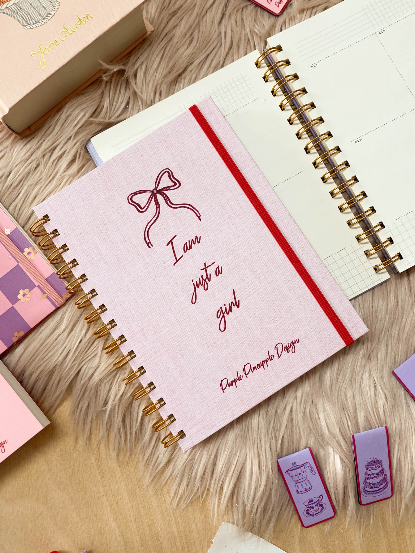 Agenda rosa com texto I am just a girl, espiral dourada, com planner e carimbos ao redor