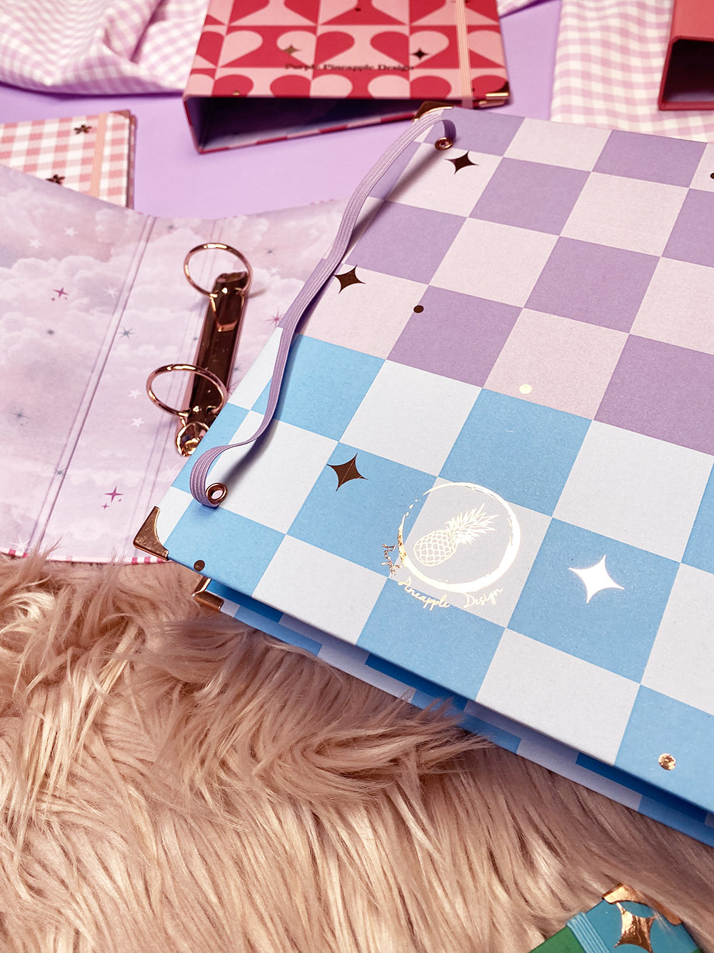 Dossiers coloridos com padrões geométricos e estrelas douradas em superfície rosa e tapete felpudo