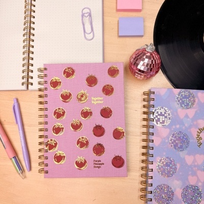 Cadernos espiral decorados com canetas, clips e acessórios em fundo de madeira