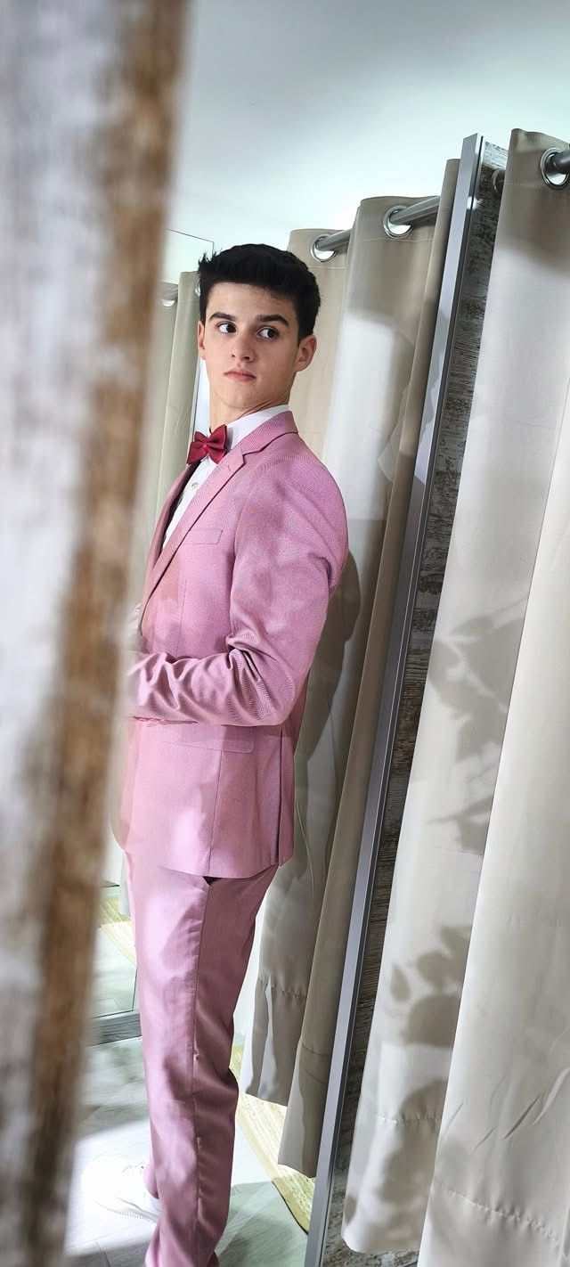 Fato Rosa Ponteado Fato cor-de-rosa com gravata borboleta vermelha em espaço com cortinas bege