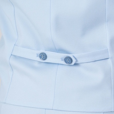 Detalhe de casaco azul claro com cinto decorativo e botões