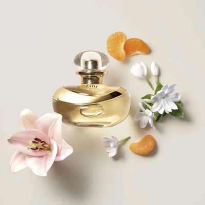 Frasco de perfume dourado com flores e tangerina em fundo bege