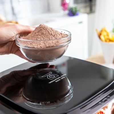 Taça de vidro com pó castanho numa balança digital preta