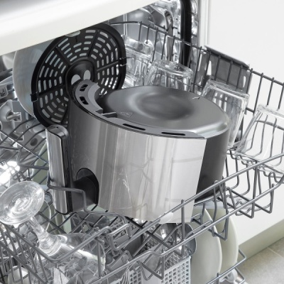 Máquina de lavar loiça aberta com utensílios metálicos e plásticos dentro