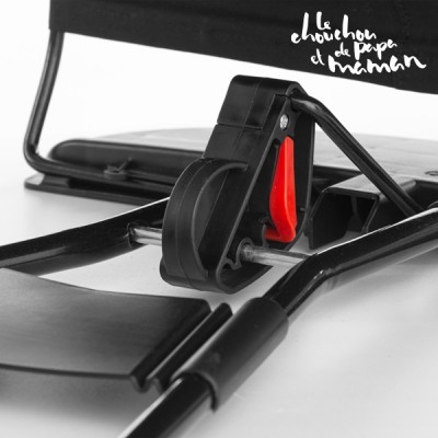 Peça metálica preta com detalhe vermelho e texto ao fundo