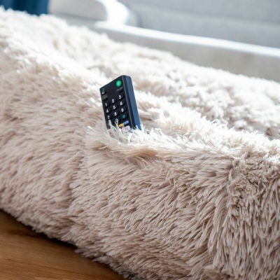 Controle remoto preto numa almofada peluda bege clara