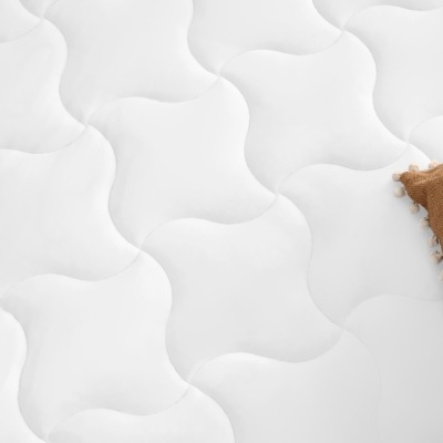 Colchão branco com padrão acolchoado e manta castanha com padrão