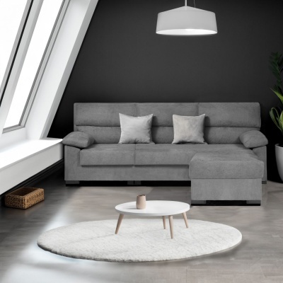 Sofá cinza com chaise longue numa sala com parede escura e mesa de centro branca com tapete redondo