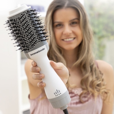 Escova secadora de cabelo InnovaGoods branca e preta com mulher segurando