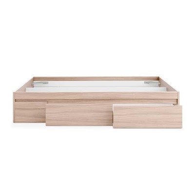 Cama de madeira clara com três gavetas abertas