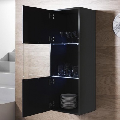 Móvel de cozinha preto com portas em vidro aberto, copos e pratos, parede de madeira clara e escadas ao fundo