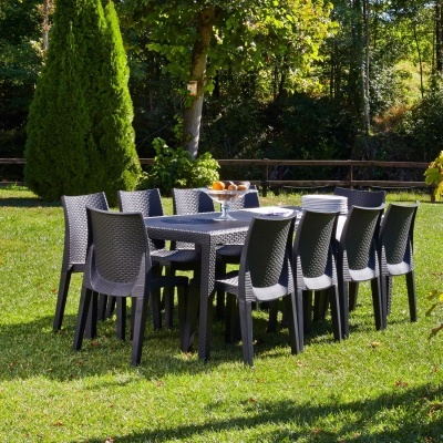Conjunto de mesa e cadeiras de jardim cinza escuro em espaço exterior com relva e árvores