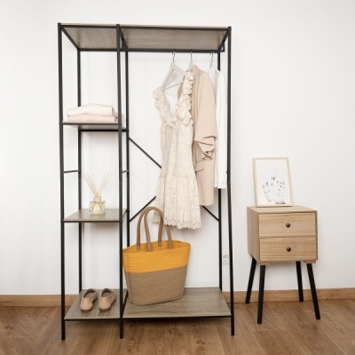 Estrutura metálica com prateleiras de madeira clara contendo roupas, saco de palha, calçado e mesa de cabeceira