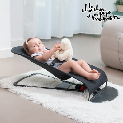 Cadeira de bebé preta reclinada com bebé sentada a segurar peluche