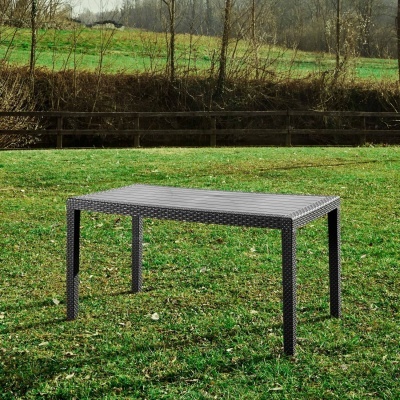 Mesa de exterior cinza escura em campo verde com árvores e cerca de madeira ao fundo