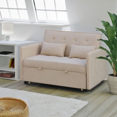 Sofá-cama bege claro com almofadas em sala luminosa com planta e mesa de apoio.